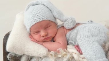 Profesyonel fotoşoplar sırasında örgü pantolon ve şapka giyen yeni doğmuş bebeğin tatlı bir şekerlemesi.