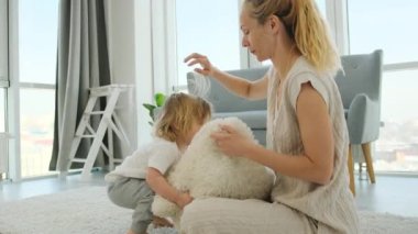 Anne unların üzerinde oturuyor ve evdeki yastıkla oğluyla oynuyor.