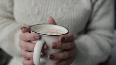 Kışın kızlar ellerindeki bardakta kakao ve marşmelov tutuyor. Bardakta sıcak içeceği olan kadın.