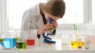 Kimya dersinde mikroskopla test sonuçlarına bakan liseli kız. Laboratuvarda okuyan kız öğrenci.