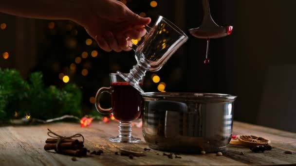 人の手は パンから複数のワインを拾うと背景にクリスマスイブライトと屋内ガラスマグカップに注ぐ 伝統的なホットアルコール飲料休日の夜 — ストック動画