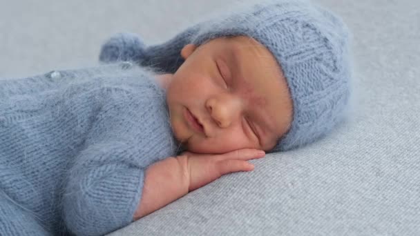 头戴针织帽子的新生儿一边睡觉一边微笑着 双手捂着头 — 图库视频影像