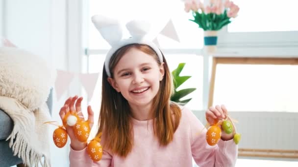 Klein Meisje Draagt Konijnenoren Handen Decoratief Geschilderde Oranje Eieren Glimlachen — Stockvideo
