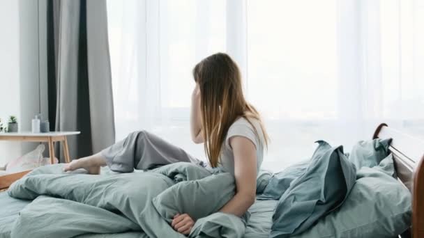 아름다운 소녀는 아침에 일어나서 잠자리에 마음을 여자가 양지바른 방에서 머리카락을 — 비디오