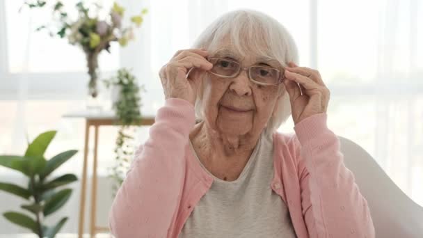 自宅で眼鏡をかけて視力を回復したシニア女性 眼鏡室内を持つ高齢女性 — ストック動画