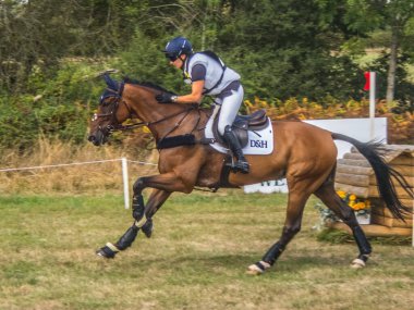 HOOK UK - AUGUST 29 2022 Rider completing the course as Wellington Horse Trials. with a fence in the background.