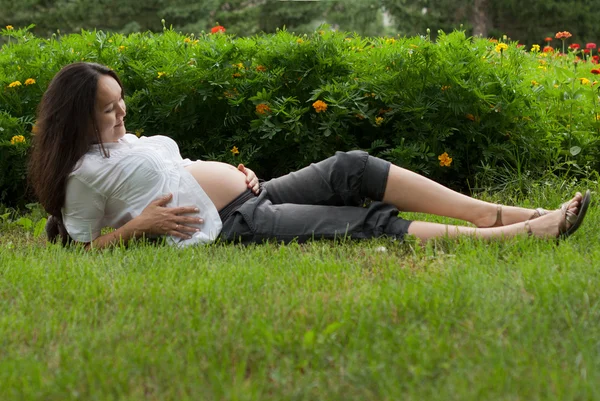 Pregnant woman relaxing on grass — Stock Photo, Image