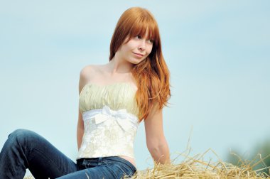 mutlu bir saman üzerinde oturan genç kız gülümseyerek