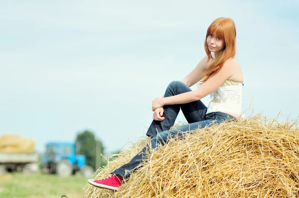 Feliz joven sonriente sentada en un heno — Foto de Stock