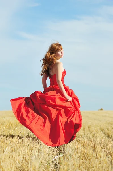 Running bride in red wedding dress in a field — Stock Photo, Image
