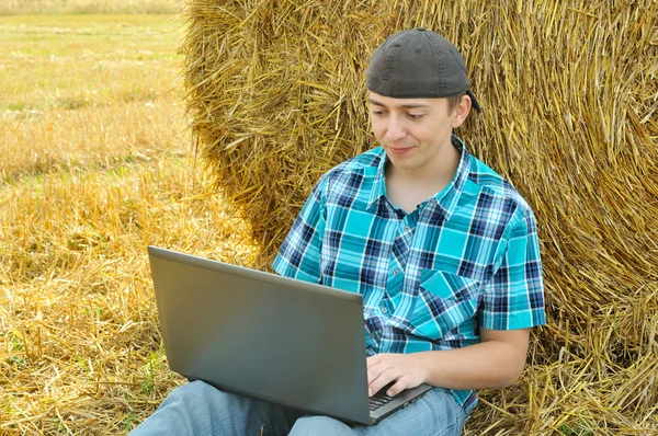 Un hombre de negocios en un campo con un ordenador portátil —  Fotos de Stock