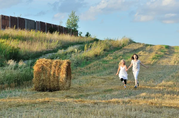 Två tjejer kör över fältet — Stockfoto