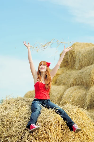 Happy smiling young girl sitting on a hay — Stock Photo, Image