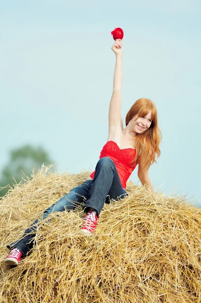 Happy smiling young girl sitting on a hay — Stock Photo, Image