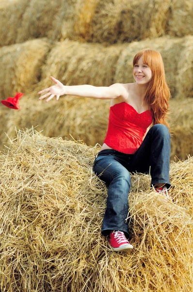 Happy smiling young girl sitting on a hay — Stock Photo, Image