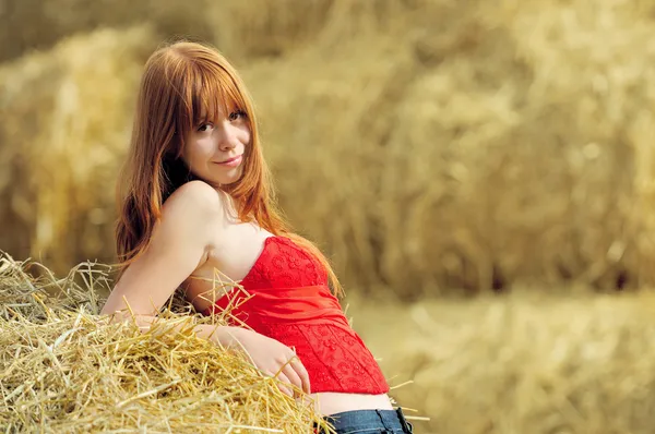 Gelukkig lachend jong meisje, zittend op een hooi — Stockfoto