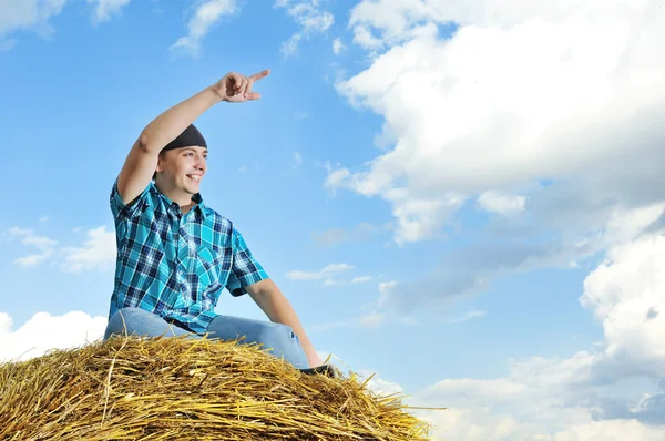 Man op een stapel van stro tegen een veld — Stockfoto