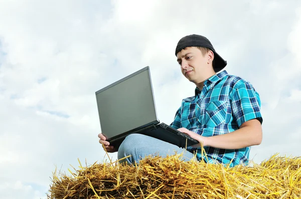 Un hombre de negocios en un campo con un ordenador portátil —  Fotos de Stock