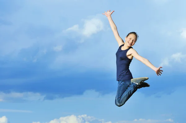 Beautiful girl in gymnastic jump against blue sky — Stock Photo, Image