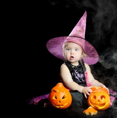 Cadılar Bayramı bebek siyah arka plan üzerinde oyulmuş kabak ile cadı