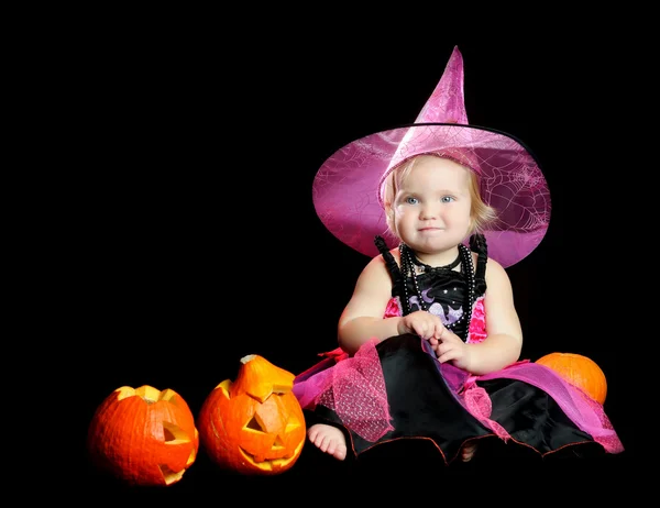 Halloween Baby Hexe mit einem geschnitzten Kürbis auf schwarzem Hintergrund — Stockfoto