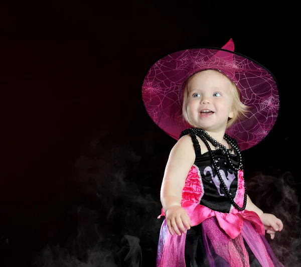 Halloween bruja bebé con una calabaza tallada sobre fondo negro — Foto de Stock