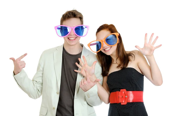 Jovem feliz sorrindo casal vestindo um grande óculos coloridos se divertindo no fundo branco — Fotografia de Stock