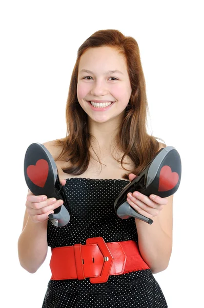 Retrato de una adolescente sonriente sosteniendo zapatos de tacón alto aislados sobre el fondo blanco — Foto de Stock