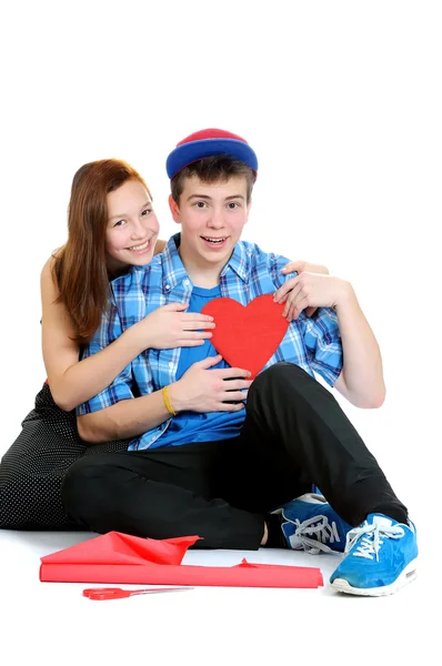 Smiling teenage girl and boy holding a valentine cut out from re — Stock Photo, Image