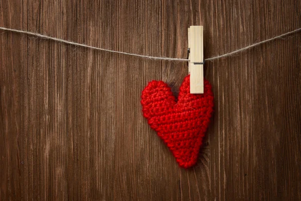 Coeur rouge suspendu sur fond en bois Image En Vente