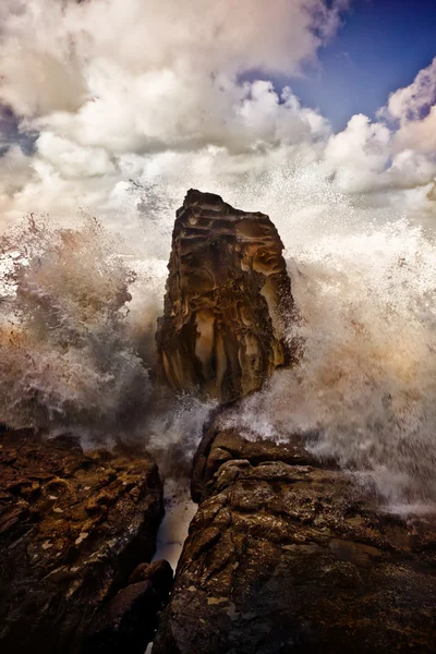Golven die breken op een rots tegen een dramatische hemel — Stockfoto