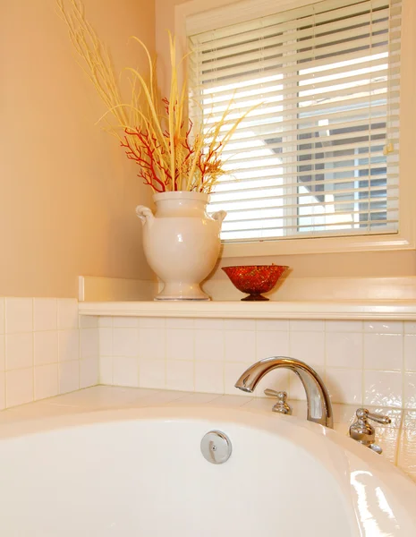 Bañera blanca con jarrón y esquina de ventana con pared beige . — Foto de Stock