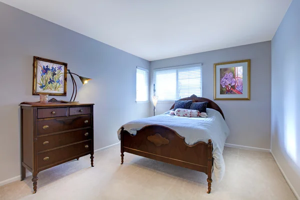 Blue bedroom with dark wood bed and dresser. — Stock Photo, Image