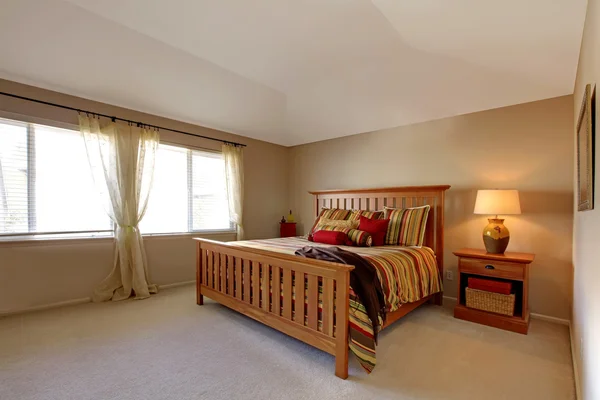 Lagre bedroom with wood bed and nightstand with stipe bedding. — Stock Photo, Image