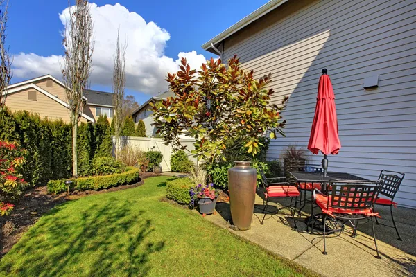 Frühlingshaus Hinterhof mit roten Stühlen und Sonnenschirm und schöne Landschaft. — Stockfoto