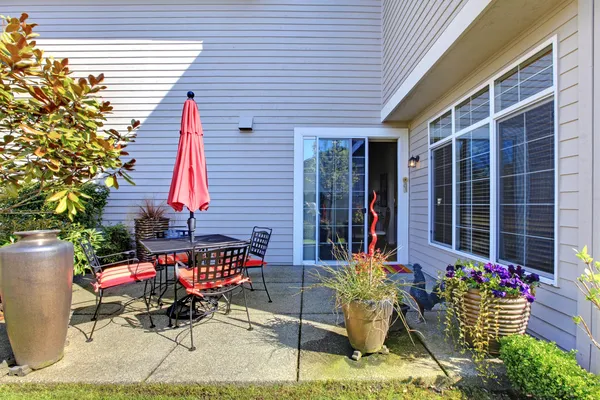 Haus Hinterhof mit Terrasse mit roten Stühlen und Sonnenschirm. — Stockfoto