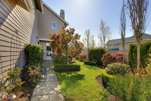 Backyard of the large beige house with walkway and nice landscape. — Stock Photo, Image