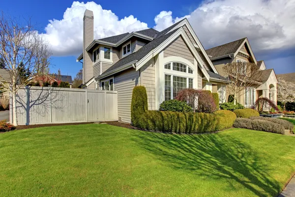 Klasyczny amerykański dom z ogrodzenia i zielonej trawie wiosną. — Zdjęcie stockowe