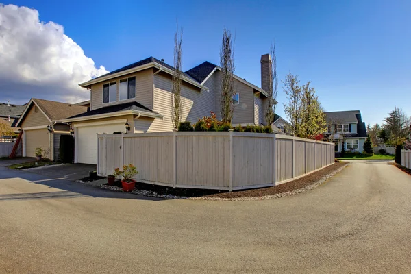 Beige hus från bakgården med garage och staket nära road. — Stockfoto