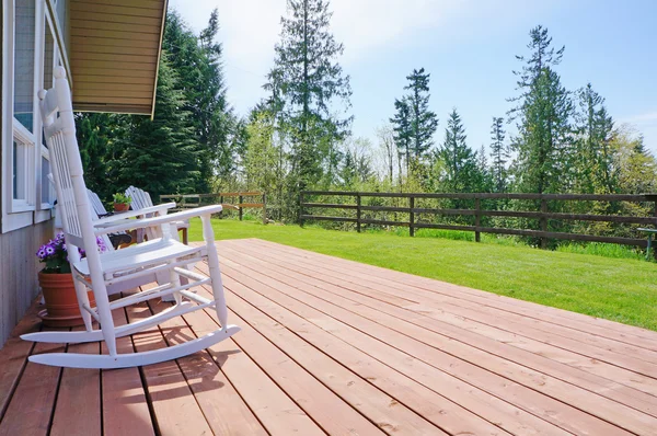 Casa de fazenda deck frontal aberto com cadeiras brancas durante a primavera . — Fotografia de Stock