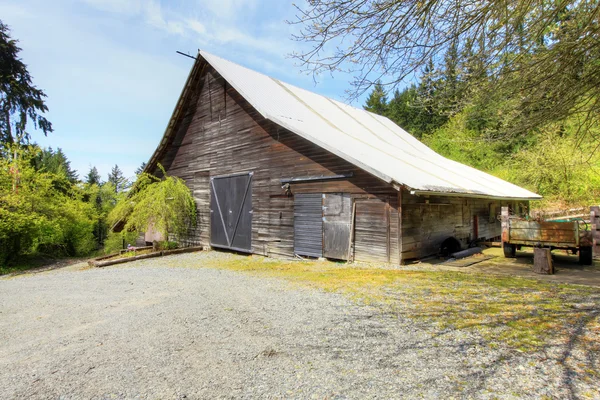 Old large shed with green spring landscape and fence. — Stock Photo, Image