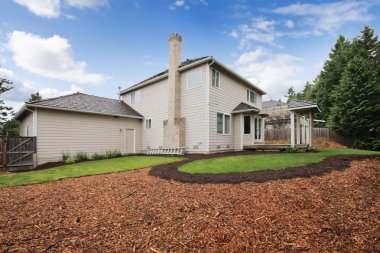 Large beige house with empty backyard during spring. clipart