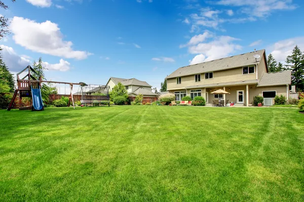 Grote prachtige omheinde achtertuin met spelen grond en huis. — Stockfoto