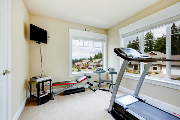 Home gym with equipment, weights and TV.