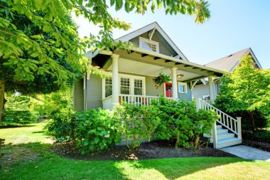 Grey small house with porch and white railings. clipart