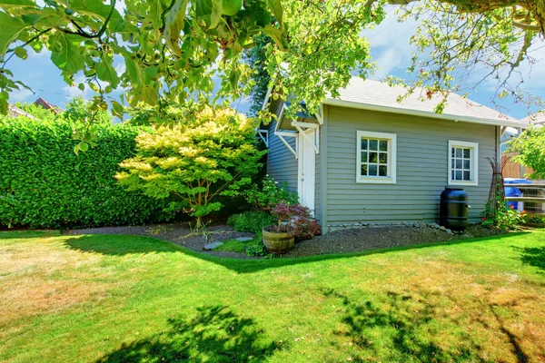 Small grey shed in the sunny green backyard. — Stock Photo, Image