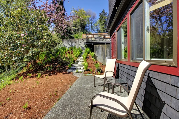 Printemps Cour arrière avec deux chaises et maison en bois noir . — Photo