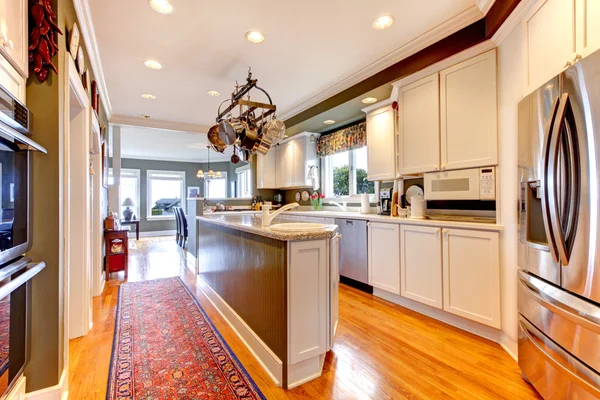 Grote witte en groene keuken met hardhouten vloer. — Stockfoto