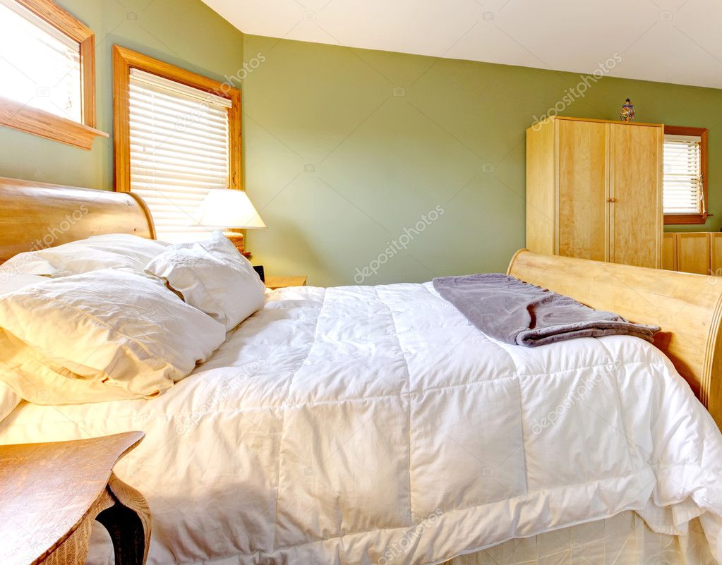 Bedroom with green walls and white bed.
