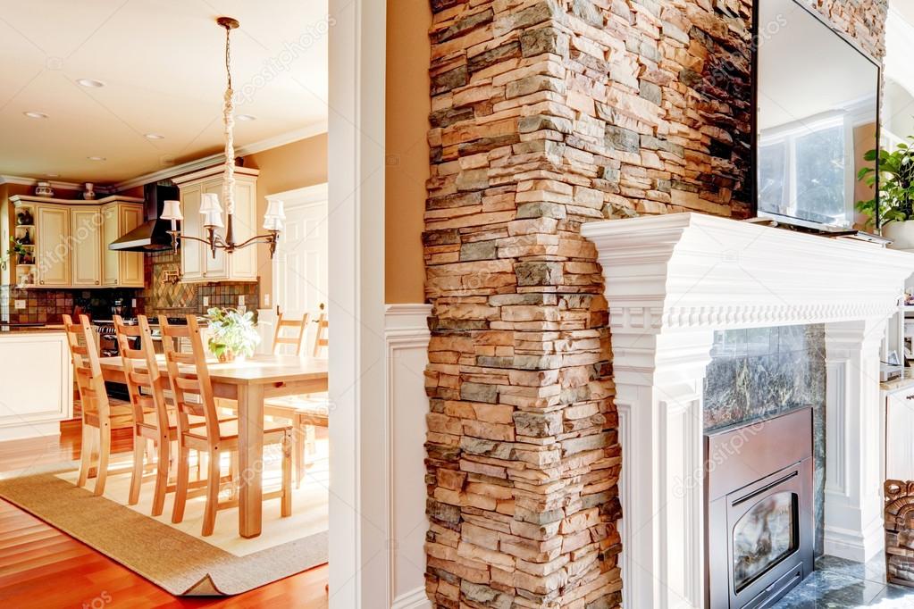 Stone fireplace with tv and dining room and kitchen.
